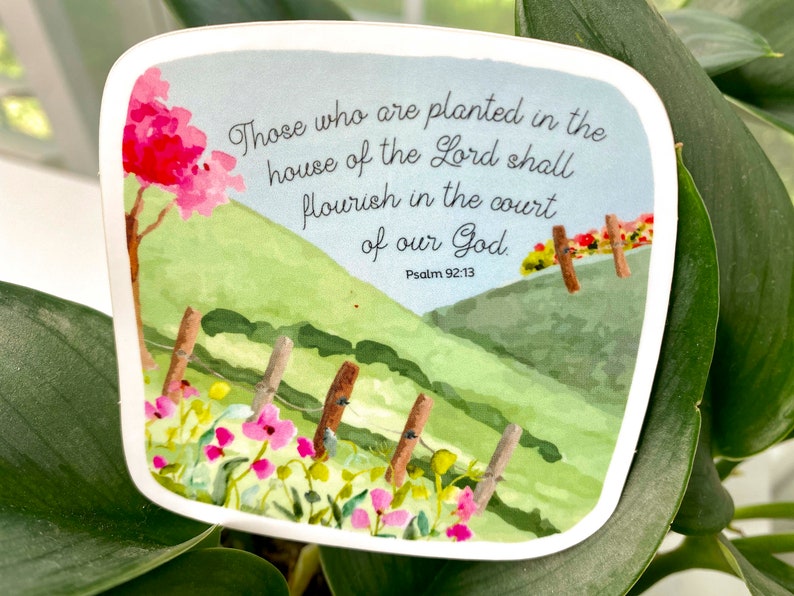 May include: A watercolor illustration of a green hillside with a fence and pink flowers. The text reads "Those who are planted in the house of the Lord shall flourish in the court of our God. Psalm 92:13".