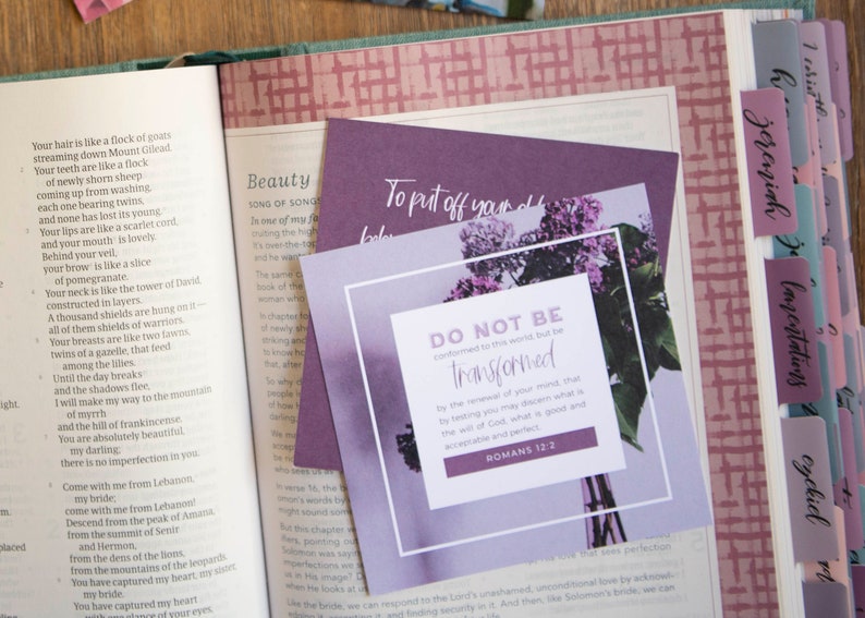 May include: A purple and white inspirational quote card with a floral design. The quote reads "Do not be conformed to this world, but be transformed by the renewal of your mind, that by testing you may discern what is the will of God, what is good and acceptable and perfect." Romans 12:2