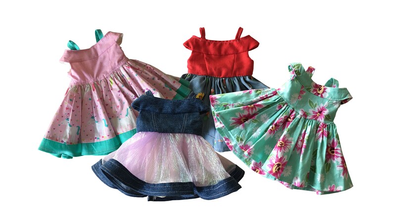 May include: Four colorful doll dresses. One pink dress with a unicorn pattern, a red dress, a denim dress with a pink tulle skirt, and a turquoise dress with a floral pattern. Each dress has a unique design.
