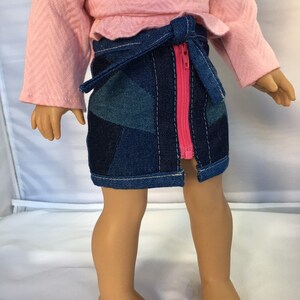 May include: A denim skirt with a pink zipper and a matching pink fabric belt. The skirt is made of patchwork denim and has a frayed hem.