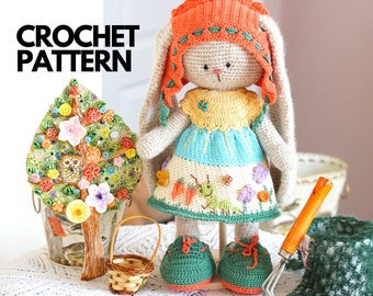 May include: Crochet pattern for a bunny wearing a dress and a hat. The bunny is holding a small basket and is standing on a table with a green tablecloth. The bunny is surrounded by other crocheted items, including a tree and a rake.