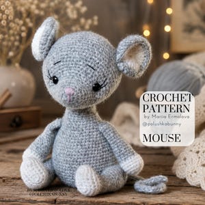 Può includere: Un topo all'uncinetto grigio con interno delle orecchie bianco e piedi bianchi. Il topo ha occhi neri con ciglia e un piccolo naso rosa. Un'etichetta rettangolare bianca riporta il testo: CROCHET PATTERN by Mariia Ermolova @polushkabunny MOUSE.
