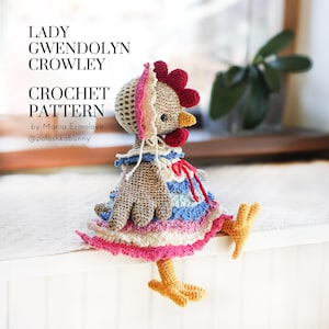 May include: A crocheted chicken doll with a red comb, yellow beak, and a bonnet. It wears a layered dress in pink, blue, and white. The image includes text: "LADY GWENDOLYN CROWLEY CROCHET PATTERN". The doll is handmade.