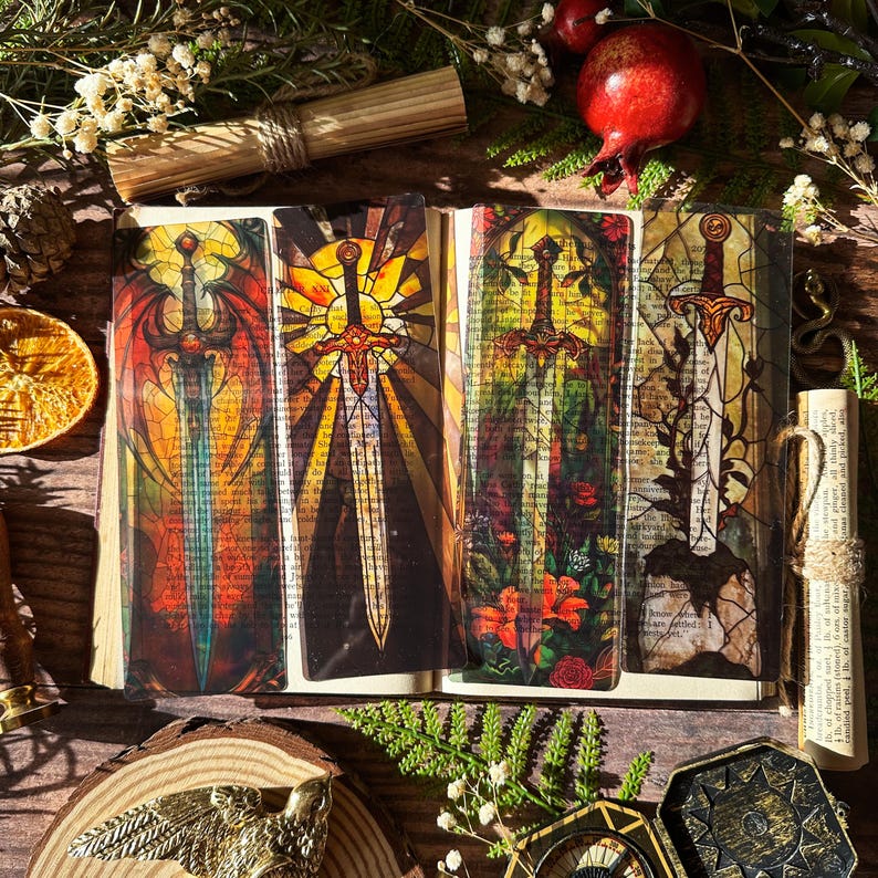 May include: Four colourful bookmarks featuring stained glass style images of swords. Each bookmark has a different design with a sword in the centre. The swords are surrounded by different colours and patterns.