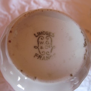 May include: Close-up of the base of a white porcelain teacup with a gold inscription that reads "LIMOGES W.G. & Co. FRANCE".
