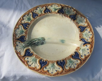 May include: A white ceramic divided serving plate with a raised design of stylized flowers in shades of blue, green, and brown. The plate has a central section and two smaller sections on either side.