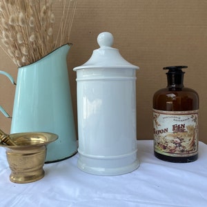 May include: White ceramic jar with a lid, a light blue jug, a brass mortar and pestle, and a brown glass bottle with a label that reads "Parfumerie Brittania Savon Fin".
