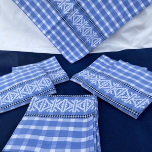 May include: Set of six blue and white checked kitchen towels with a white embroidered design. The towels have a black border.