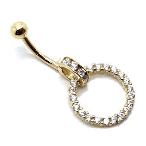 May include: Gold belly button ring with a clear crystal circle charm. The charm is set with small clear crystals.