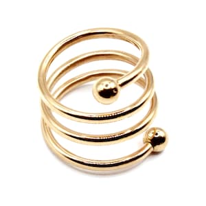 May include: Gold-toned spiral ring with two round balls at the ends. The ring is made of multiple coils of metal.