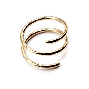 May include: A gold-toned double spiral ring. The ring is made of two intertwined bands of metal.
