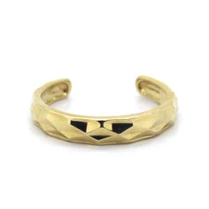 May include: A gold toe ring with a textured, geometric design.