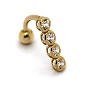 Könnte beinhalten: Goldener Körperschmuck mit einer gebogenen Stange und fünf klaren runden Steinen.