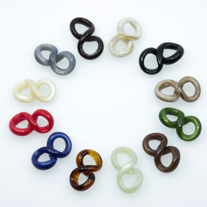 Puede incluir: Doce pinzas para el pelo de plástico en forma de infinito en varios colores, incluyendo rojo, azul, verde, marrón, negro, blanco y gris.