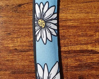 Könnte beinhalten: Ein blauer und weißer Schlüsselanhänger mit einem Gänseblümchenmuster und einem silbernen Schlüsselring.