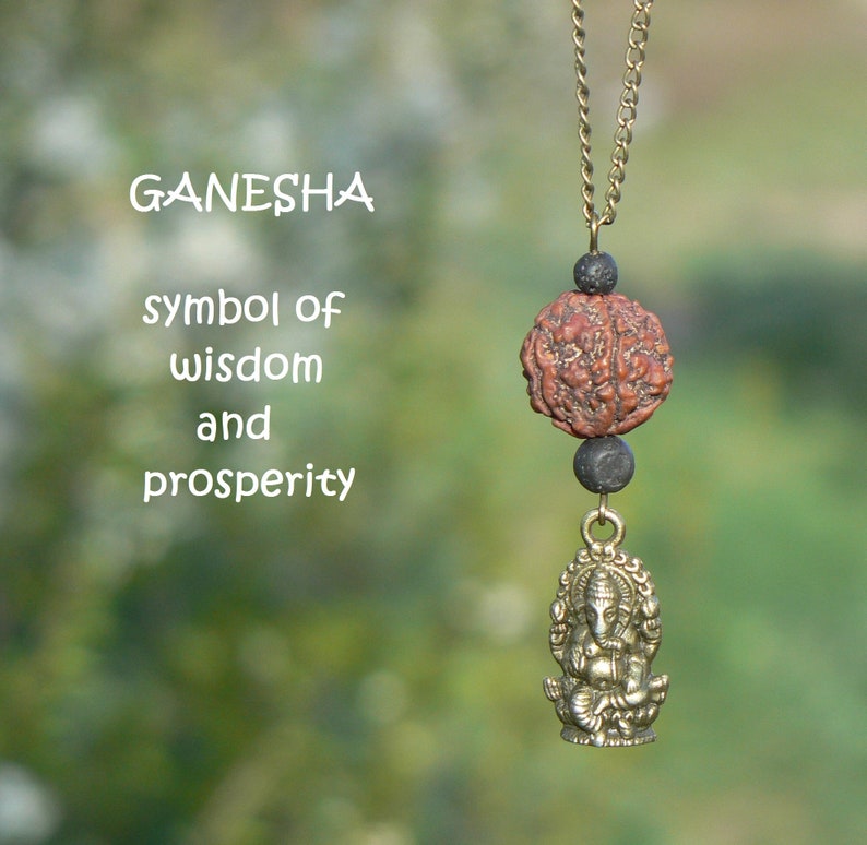 Puede incluir: Un collar de oro con una cuenta marr&oacute;n y negra y un peque&ntilde;o colgante de oro de la deidad hind&uacute; Ganesha. El texto "GANESHA s&iacute;mbolo de sabidur&iacute;a y prosperidad" est&aacute; escrito debajo del collar.