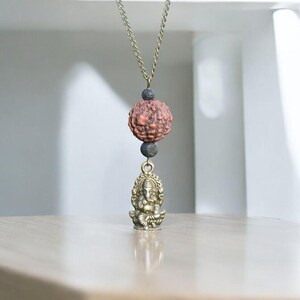 Puede incluir: Un collar de oro con una cuenta marr&oacute;n y negra y un peque&ntilde;o colgante de oro de la deidad hind&uacute; Ganesha.