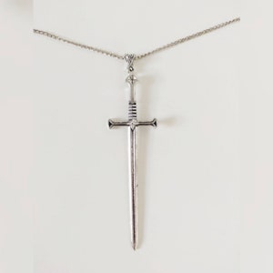 Op de afbeelding: Een zilveren zwaard ketting met een hanger. Het zwaard heeft een gedetailleerd ontwerp en een puntige punt.