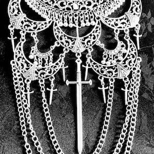 May include: A silver necklace with a large, ornate pendant featuring a sword design. The pendant is surrounded by smaller, crescent-shaped charms and hangs from a chain with multiple layers.
