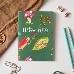 May include: A green notebook with the words "Nature Notes" on the front cover. The cover features illustrations of a ladybug, a caterpillar, a mushroom, and flowers.