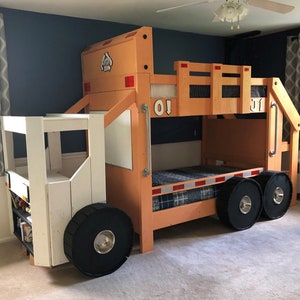 May include: A wooden bunk bed shaped like a garbage truck. The top bunk is orange and the bottom bunk is white. The bed has two large black wheels and a smaller black wheel on the front. The bed has a ladder on the side and a railing on the top bunk.