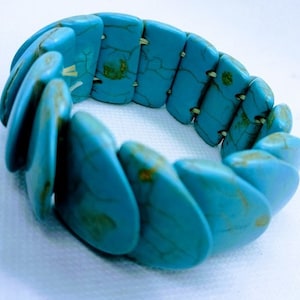 May include: A turquoise stretch bracelet made of rectangular, rounded stones. The stones are a vibrant blue-green colour with brown veining. The bracelet is designed to stretch and fit various wrist sizes.