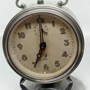 old Jas 60s mechanical alarm clock silver metal color with colored numbers in very good working condition  decoration