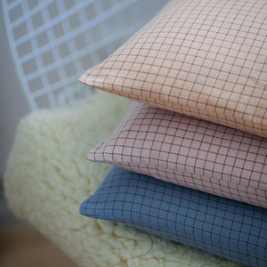 May include: Three decorative pillows with a checkered pattern. The top pillow is light pink with black checks, the middle pillow is a darker pink with black checks, and the bottom pillow is a dark blue with black checks.