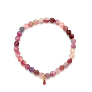 May include: A pink, purple and red gemstone bracelet with a small, dangling gemstone charm.