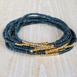 May include: A multi-strand beaded bracelet with teal blue and gold beads. The bracelet is made of several strands of small beads, with a row of gold beads at the bottom.