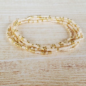 May include: A multi-strand beaded bracelet with alternating gold and cream colored beads.