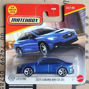 May include: A Matchbox toy car package featuring a blue 2024 Subaru WRX S4 STI model. The package includes the Matchbox logo, the text "NEW NOUVEAU 2025", and the number 31/125. The car is a die-cast metal model.