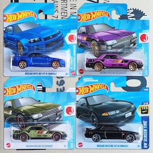 May include: Four Hot Wheels die-cast toy cars in original blister packaging. The collection includes a blue Nissan Skyline GT-R (BNR34), a purple Nissan Skyline RS (KDR30), an olive green Nissan Skyline RS (KDR30), and a black Nissan Skyline GT-R (BNR32).