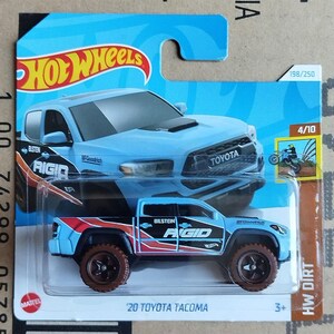 May include: A die-cast Hot Wheels toy truck, a '20 Toyota Tacoma, in a light blue colour scheme with red and black accents. The toy truck has brown wheels and the text "RIGID" and "BILSTEIN" on the side. The packaging includes the Hot Wheels logo.