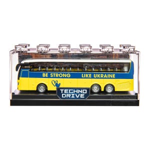 May include: A yellow and blue toy bus with the text "BE STRONG LIKE UKRAINE" and "TECHNO DRIVE". The bus is in a clear display case with a black base. The bus has four sets of wheels.