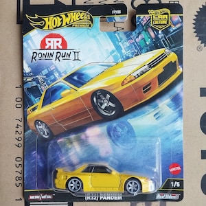 May include: A Hot Wheels Premium die-cast car, featuring a yellow Nissan Skyline (R32) Pandem model. The packaging includes the "Ronin Run II" series logo and "Car Culture" branding. The car is a 1/5 scale model with Real Riders tires.