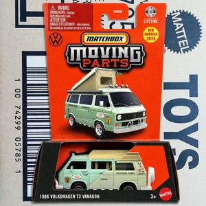 May include: A Matchbox Moving Parts 1986 Volkswagen T3 Vanagon die-cast toy vehicle in light green with a pop-up roof. The packaging features an orange card with the text Matchbox Moving Parts, Volkswagen logo, and Mattel branding.