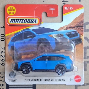 Könnte beinhalten: Ein blaues 2023 Subaru Outback Wilderness Druckguss-Spielzeugauto in der Matchbox-Originalverpackung. Die Karte zeigt eine Grafik des Fahrzeugs in einer Wüstenlandschaft, das Matchbox-Logo sowie den Text 99/125, C0859 und Designed for a Lifetime.