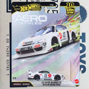 May include: A Hot Wheels Premium Aero Styles die-cast toy car, the LB Super Silhouette Nissan Silvia (S15), featuring a white body with black and red racing decals, the number 23, and Liberty Walk branding, packaged on a colourful blister card.