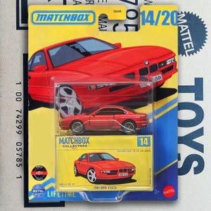Puede incluir: Un modelo a escala Matchbox Collectors de un coche rojo BMW 850CSi de 1994, empaquetado en una tarjeta amarilla y azul. La tarjeta presenta una gran ilustración del coche y el logotipo de Matchbox. El paquete está marcado "14/20".