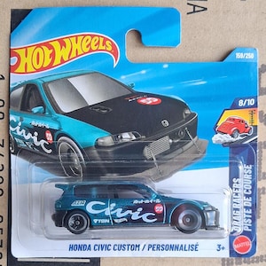 Könnte beinhalten: Ein teal-farbenes und schwarzes Hot Wheels Honda Civic Custom Druckgussauto. Das Auto hat das Wort "Civic" in weißer Schrift auf der Seite, zusammen mit der Nummer "59". Die Verpackung enthält das Hot Wheels-Logo und den Text "Drag Racers".