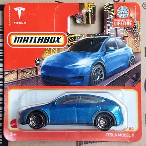 May include: A blue Matchbox Tesla Model Y die-cast toy car in its original red and white blister packaging. The packaging features a graphic of the car on a bridge, the Tesla logo, and the text Designed for a Lifetime and Tesla Model Y.
