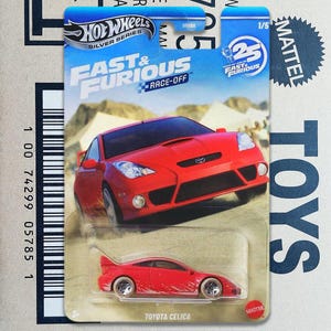 May include: A Hot Wheels Fast & Furious Race-Off die-cast toy car in red, featuring a Toyota Celica model. The packaging displays the car in a blister pack with blue branding, a 25th anniversary logo, and the text Fast & Furious Race-Off.