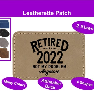 Op de afbeelding: Beige lederen patch met zwarte stiksels en de tekst "RETIRED 2022 NOT MY PROBLEM Anymore".