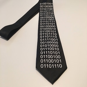 May include: A black tie with white binary code printed on it. The code includes the numbers 0 and 1.