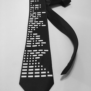 May include: A black silk tie with a white pattern of Morse code dots and dashes. The tie has the words "morse code" printed at the top.