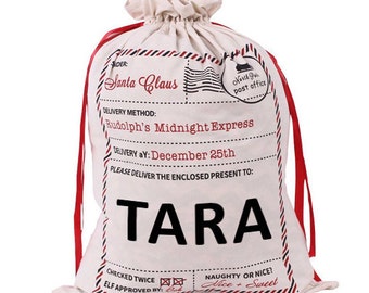 May include: A white canvas Santa sack with red drawstrings. The sack has a printed design that looks like a vintage post office mail bag. The text on the sack reads "Santa Claus", "Rudolph's Midnight Express", "Delivery aY: December 25th", and "Please deliver the enclosed present to: TARA".