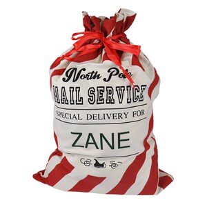 May include: A red and white striped Santa sack with the text "North Pole Mail Service" and "Special Delivery For Zane".