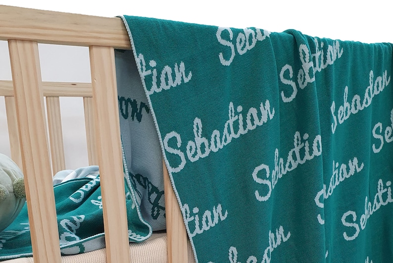 May include: A teal blue knitted baby blanket with the name "Sebastian" embroidered in white on it.
