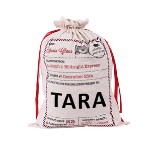May include: White canvas Santa sack with red ribbon ties. The sack has a printed label that says "Santa Claus" and "Rudolph's Midnight Express". The label also says "Delivery by: December 25th" and "Please deliver the enclosed present to: TARA".